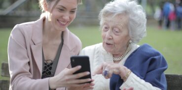 En ung kvinna visar en äldre kvinna någonting på en mobilskärm