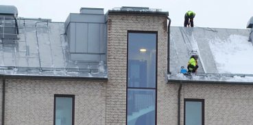 Personer som skottar snö från taket