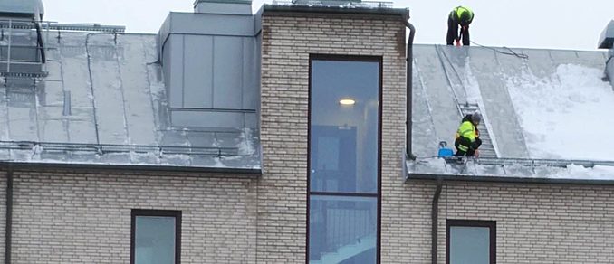 Personer som skottar snö från taket