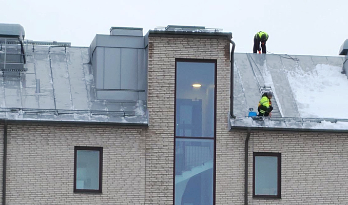 Personer som skottar snö från taket