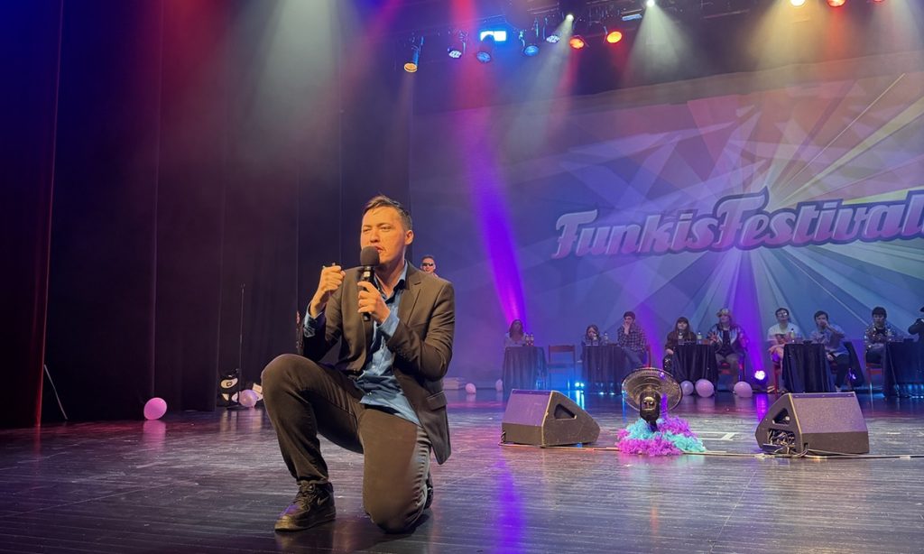 Artist i kostym står på ett knä och sjunger