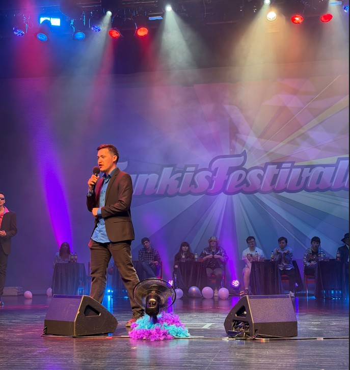 Kille sjunger på scenen med publik bakom