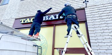 Personer på stege som sätter upp en neonskylt