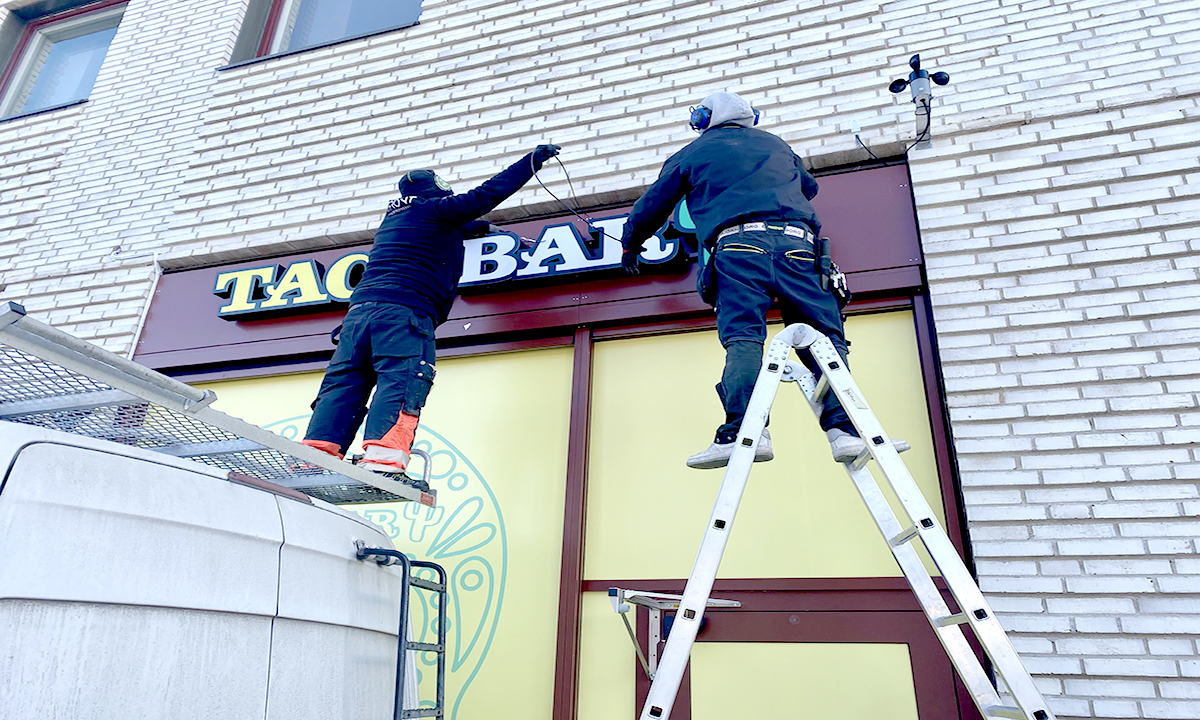 Personer på stege som sätter upp en neonskylt