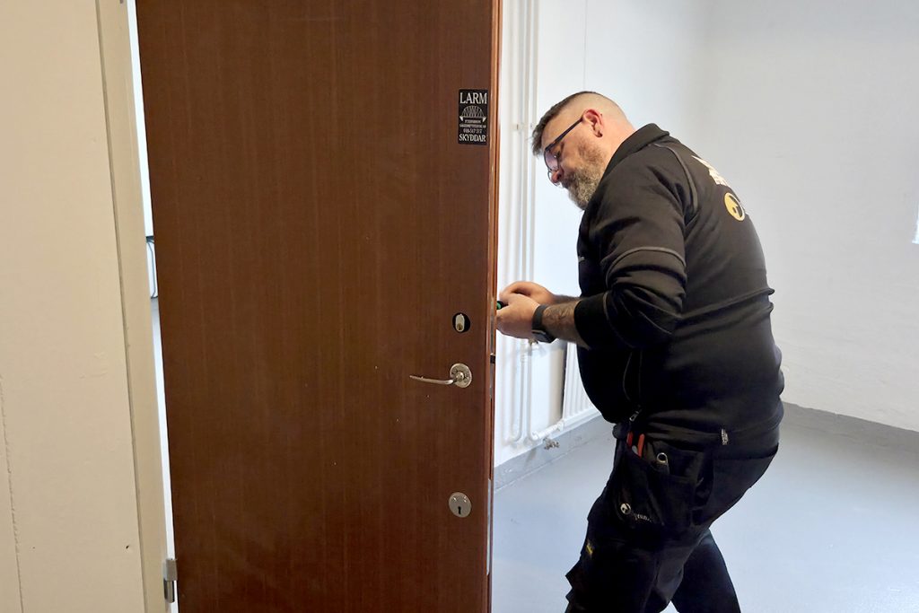 Fixar låset på en dörr i trapphuset. 