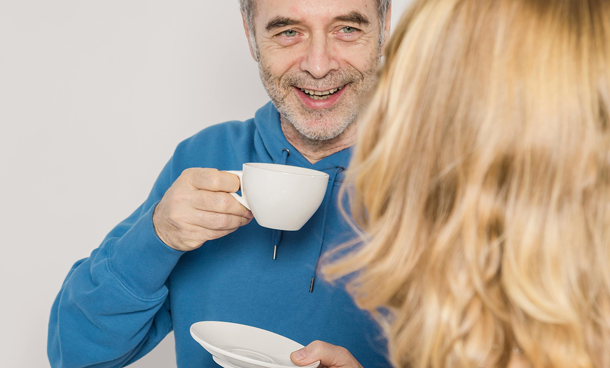 Glad person som dricker kaffe och samtalar med annan person