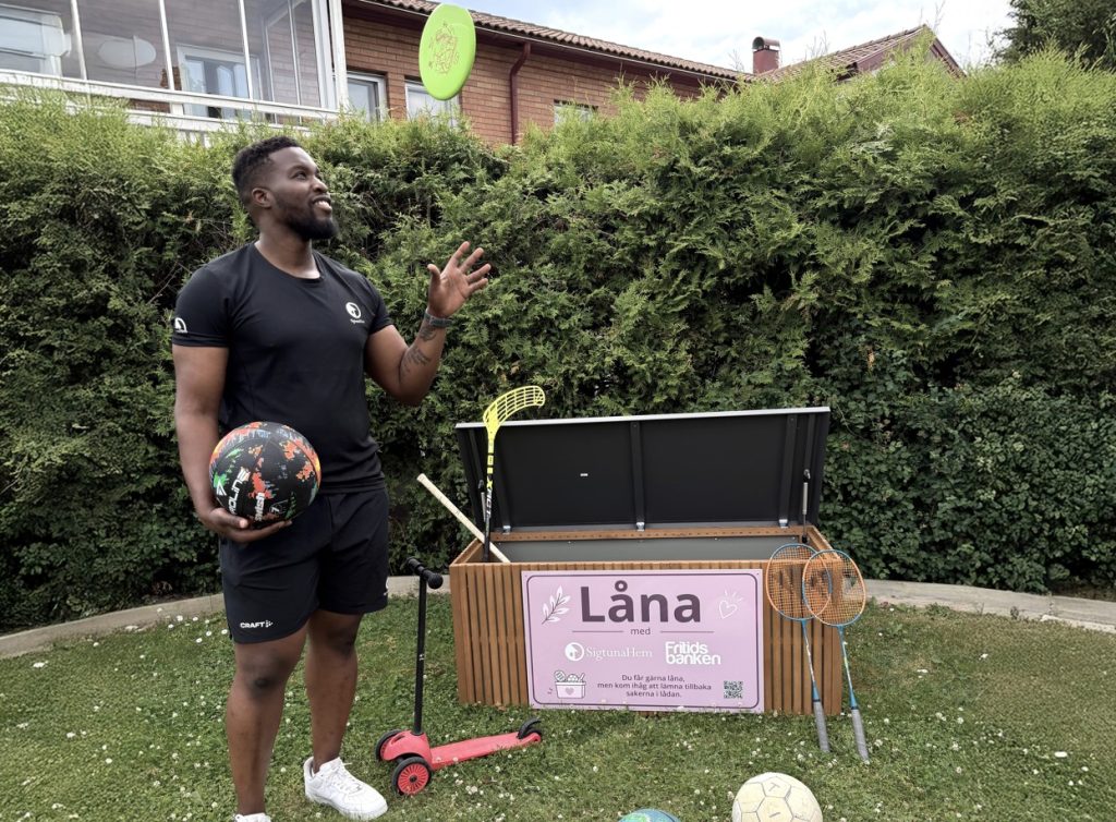 Jonathan leker med en frisbee framför en utlåningslåda med sportartiklar