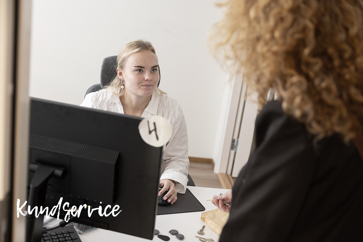 Kvinna som sitter bakom en disk med dator